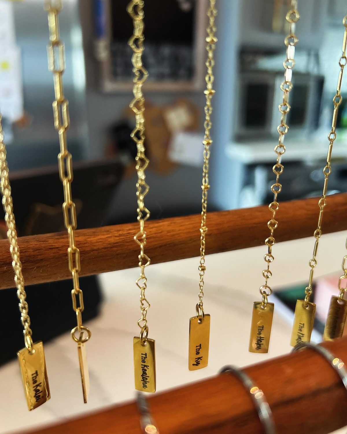 14k gold filled chains hanging on a wooden rack, each with a small engraved name tag