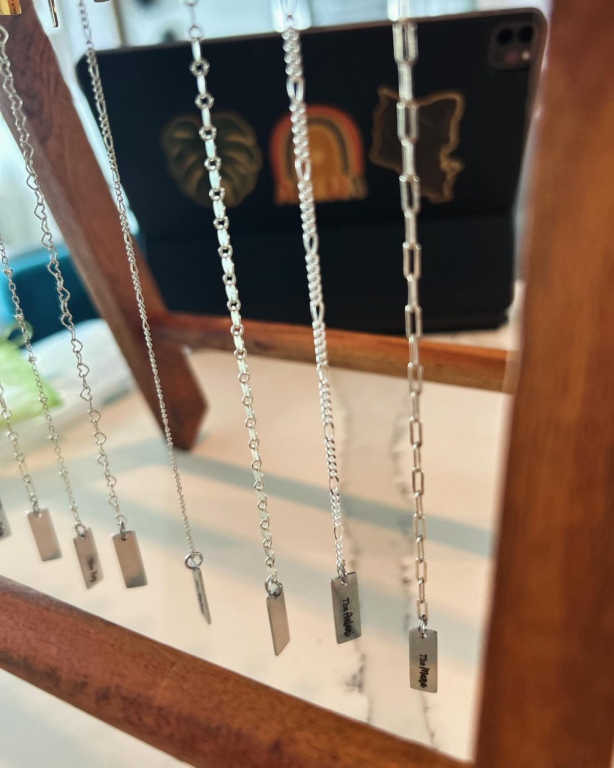 Sterling silver chains hanging on a wooden rack, each with a small engraved name tag